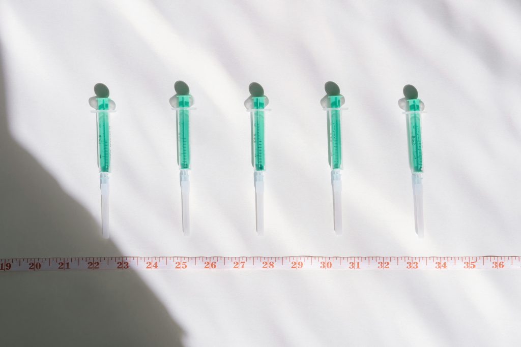 Syringes lined up next to a tape measure